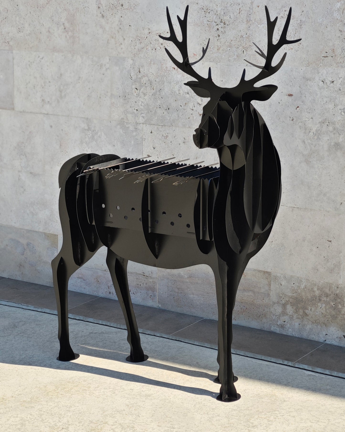 Black metal deer grill against a light stone wall